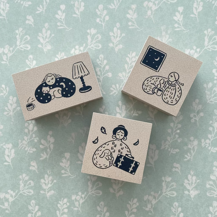 Three small square boxes with illustrated designs on a wooden surface